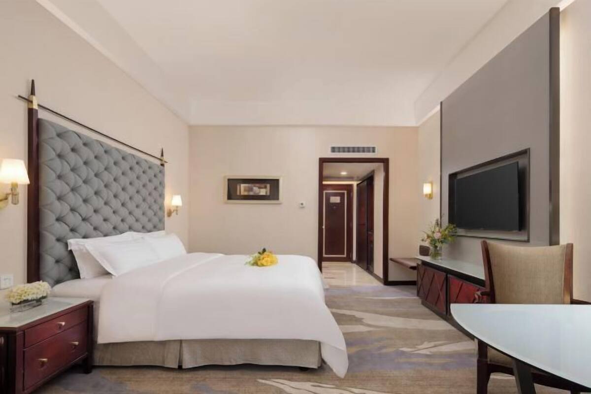 A hotel room with a large bed, a television, a desk, and a chair.