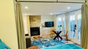 Een moderne woonkamer met een open haard, een televisie en een eetgedeelte met stoelen en een tafel.