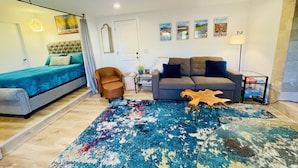 Een moderne woonkamer met een bank, een stoel, een salontafel en een bed.