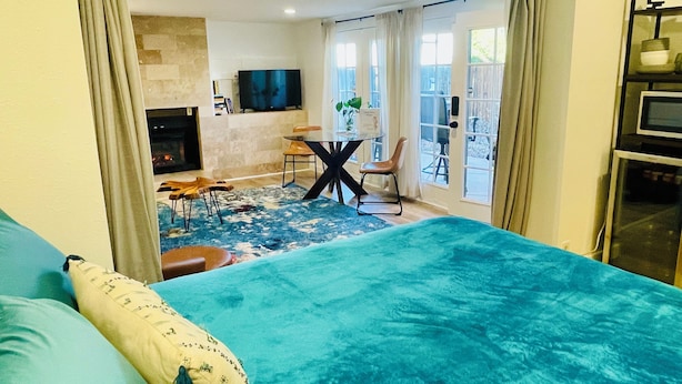 Een slaapkamer met een groot bed, een open haard, een eethoek en een balkon met uitzicht.