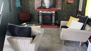 Un salon chaleureux avec des meubles en osier, une cheminée, un téléviseur et un mur décoratif.