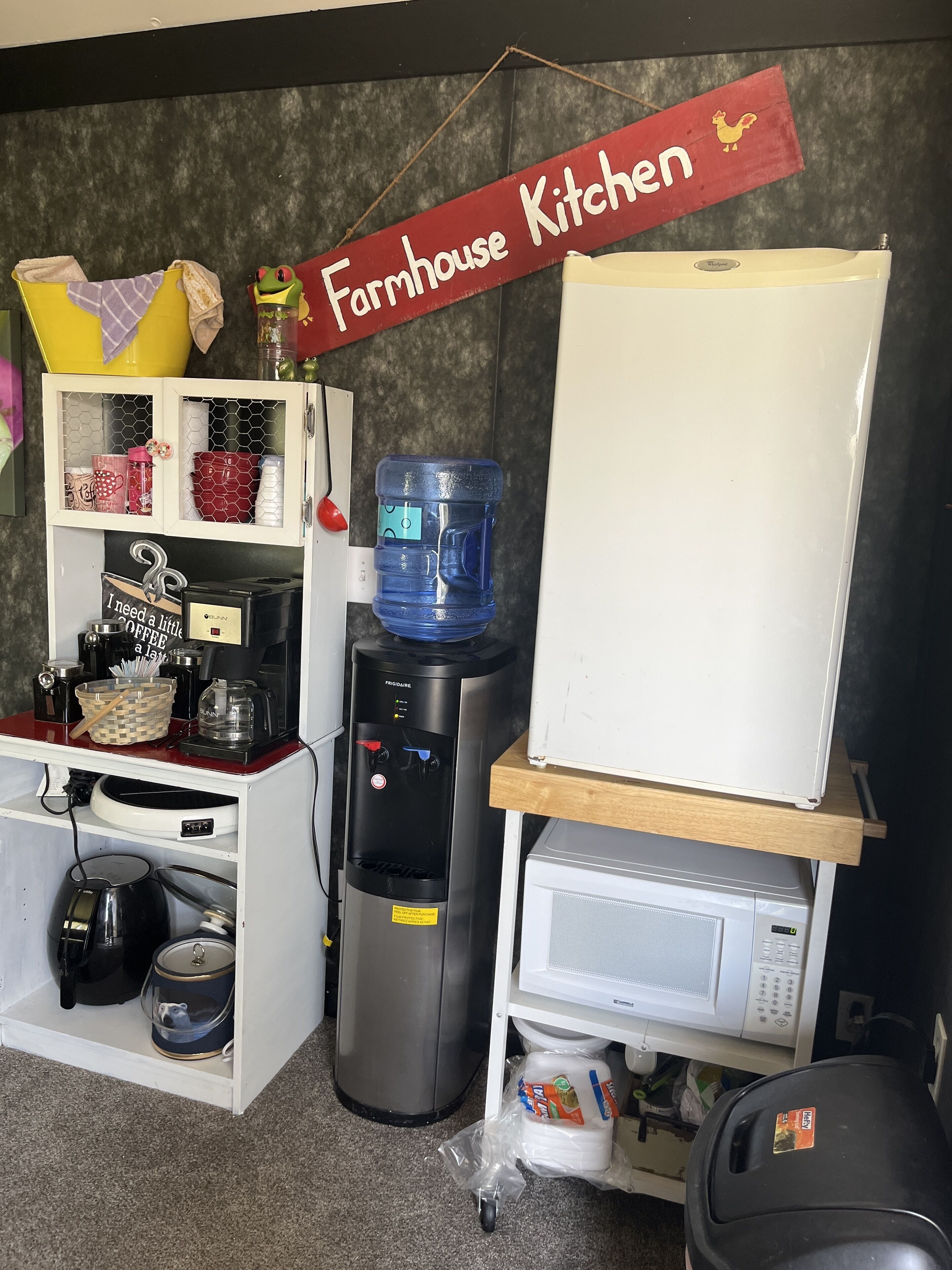 A kitchenette with a water dispenser, coffee maker, and a microwave.