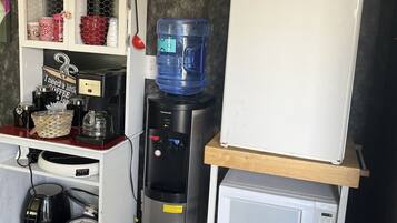 A kitchenette with a water dispenser, coffee maker, and a microwave.