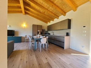 Een moderne keuken met houten balken, een eethoek met tafel en stoelen, en een televisie op een kast.