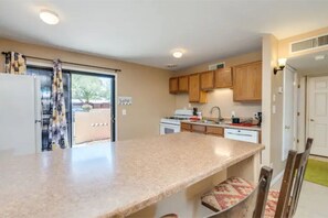 Kitchen features a central island, sink, and stove, with a window and door to an outdoor area.