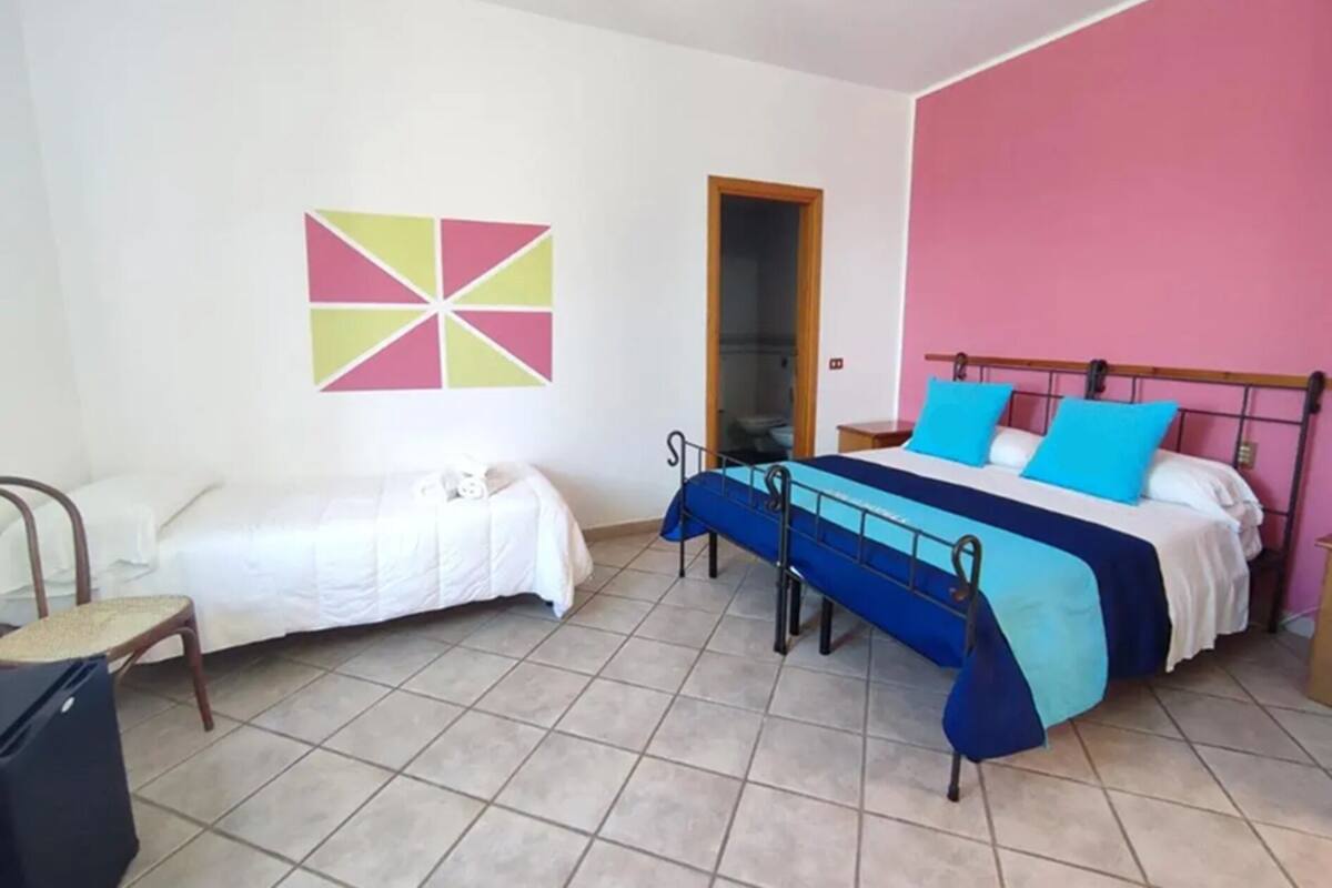 Un dormitorio con una cama, una silla, una mesita y un adorno en la pared.