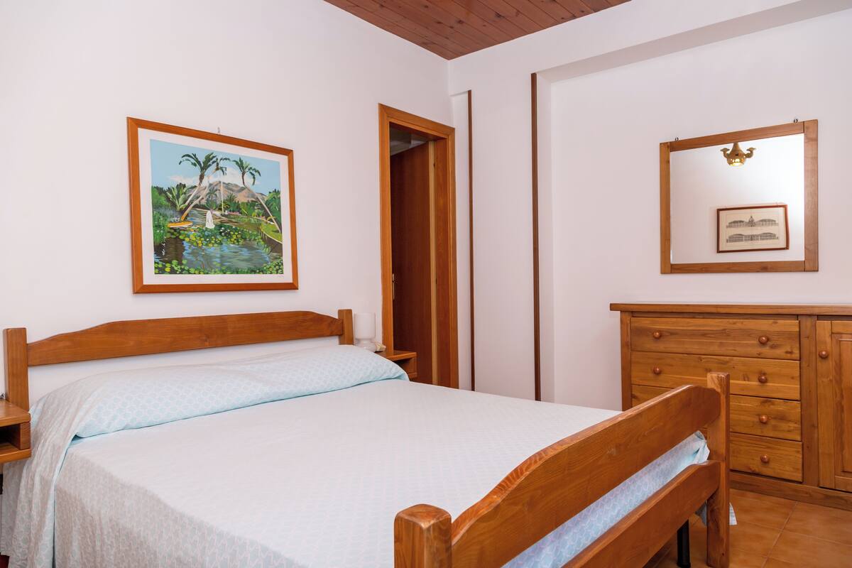 Un dormitorio con una cama y un aparador de madera, y un cuadro en la pared.