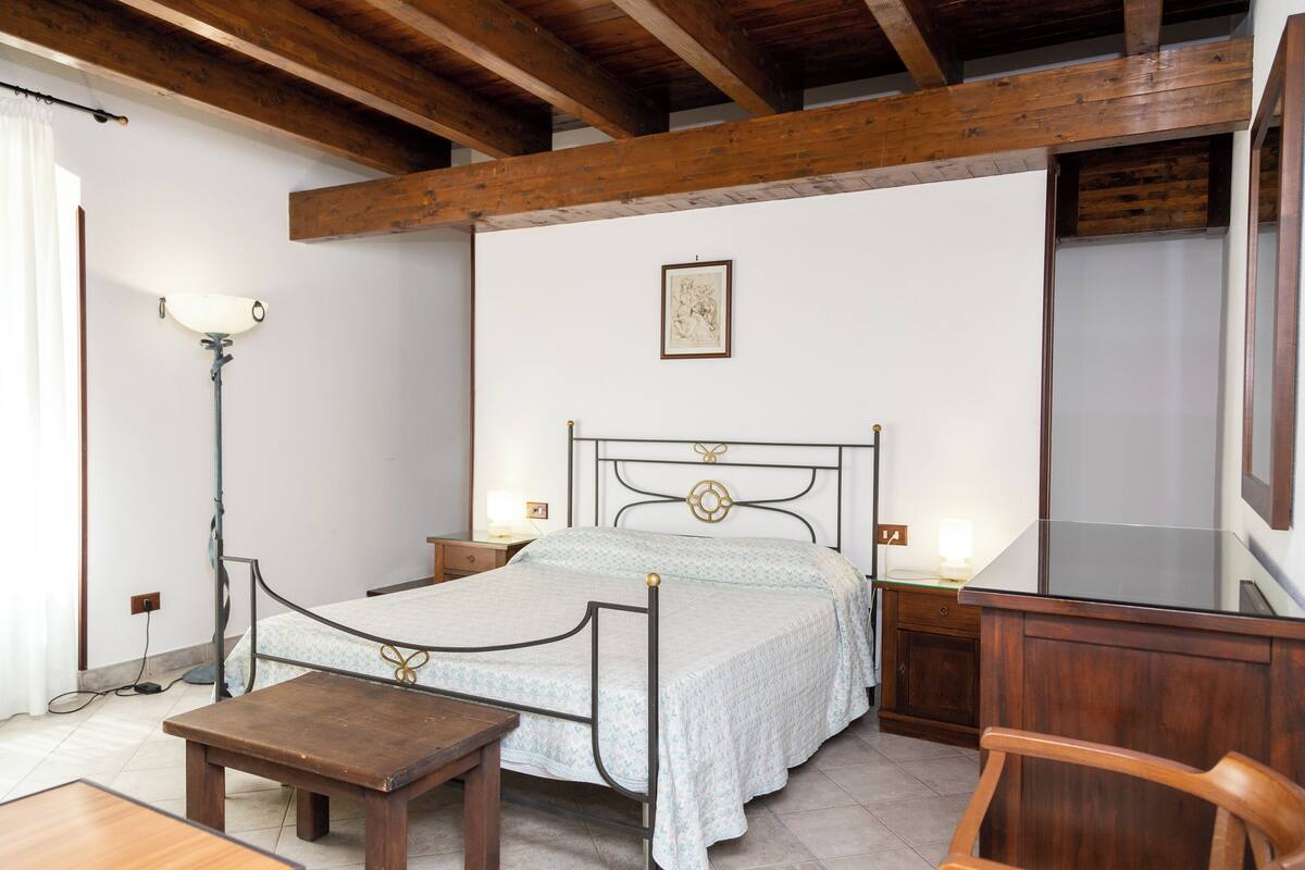 Un dormitorio con estructura de cama de madera, mesitas de noche, un escritorio y una silla.