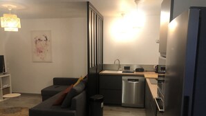 A modern kitchen with a dishwasher, a refrigerator, and a dining area with a sofa. - Villa 10 minutes from the quiet beach (Soulac-sur-Mer)