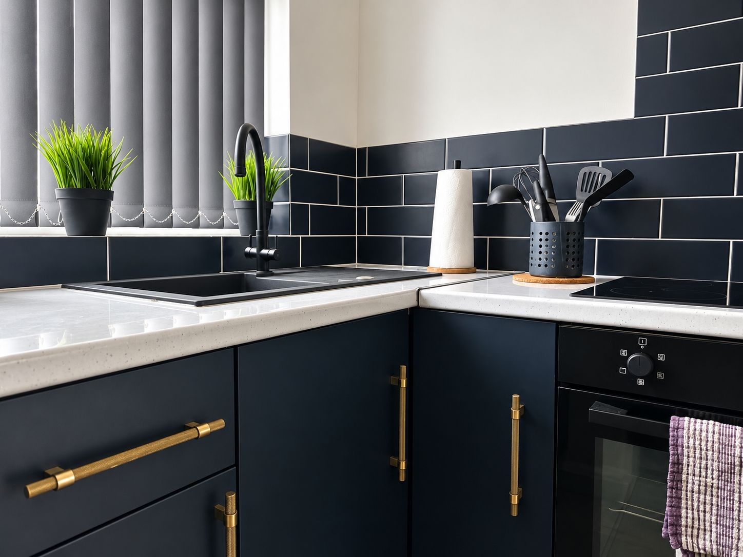 A modern kitchen with dark cabinetry, a stainless steel sink, and a built-in oven.