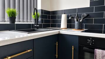 A modern kitchen with dark cabinetry, a stainless steel sink, and a built-in oven.