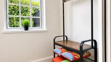 A bunk bed with a wooden top and metal frame, a window with a view of greenery, and a potted plant on the windowsill.