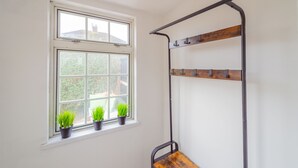 A room with a window, a metal shelf, and three potted plants.