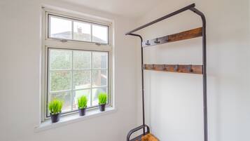 A room with a window, a metal shelf, and three potted plants.