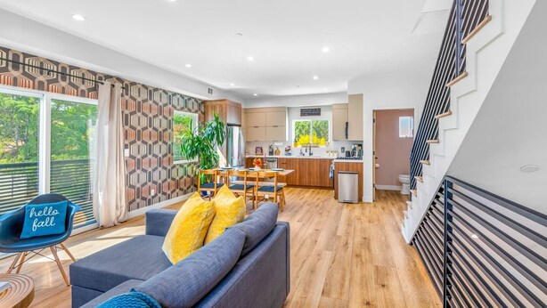 A modern living room with a sofa, a dining table, and a kitchen in the background.