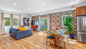A modern living room with a sofa, dining table, and a large window.
