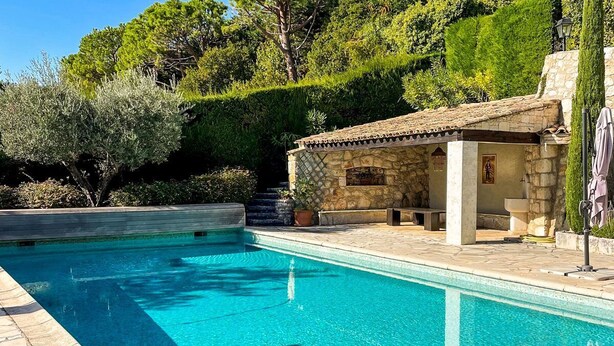 Una piscina trasparente con elementi architettonici in pietra e una panchina in pietra.