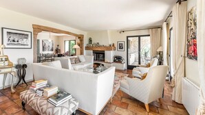 Un soggiorno spazioso con camino, un'area pranzo e una cucina visibile attraverso un arco aperto.