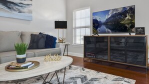 Una sala de estar con sofá, mesa de centro, televisor y aparador.