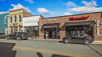 A street view with buildings including a Taproom and Moosejaw, a bike rack, and parked cars.