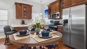 Una cocina moderna con armarios de madera, electrodomésticos de acero inoxidable y una mesa redonda con sillas para cuatro.