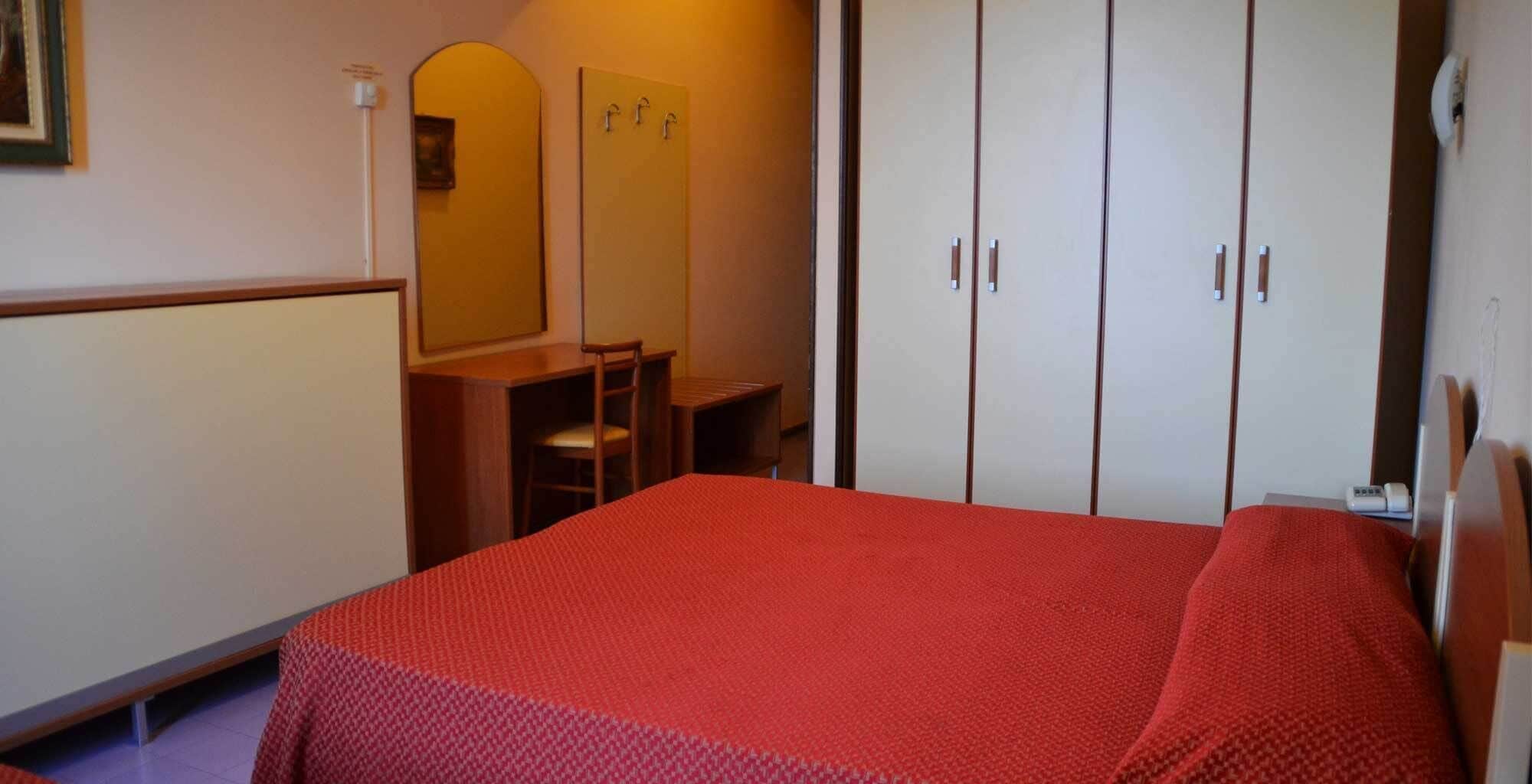 A bedroom with a bed, a desk, a chair, and a wardrobe.