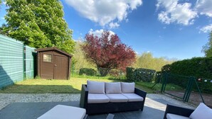 A patio area with wicker furniture and a small shed.