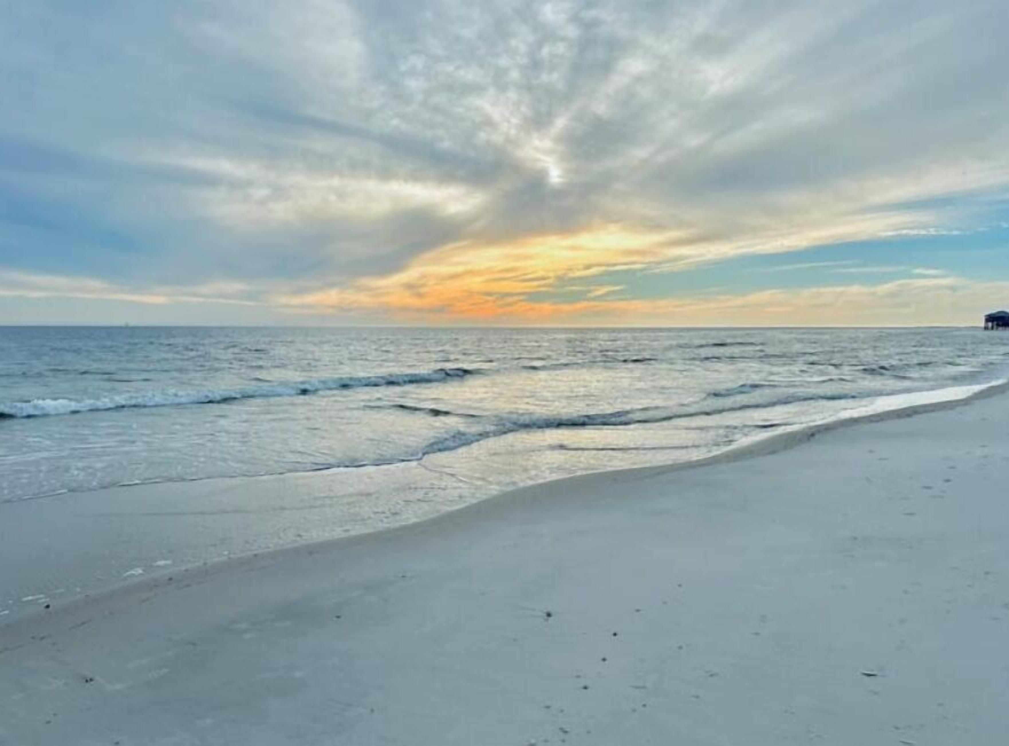Une plage avec une mer calme et un ciel nuageux.