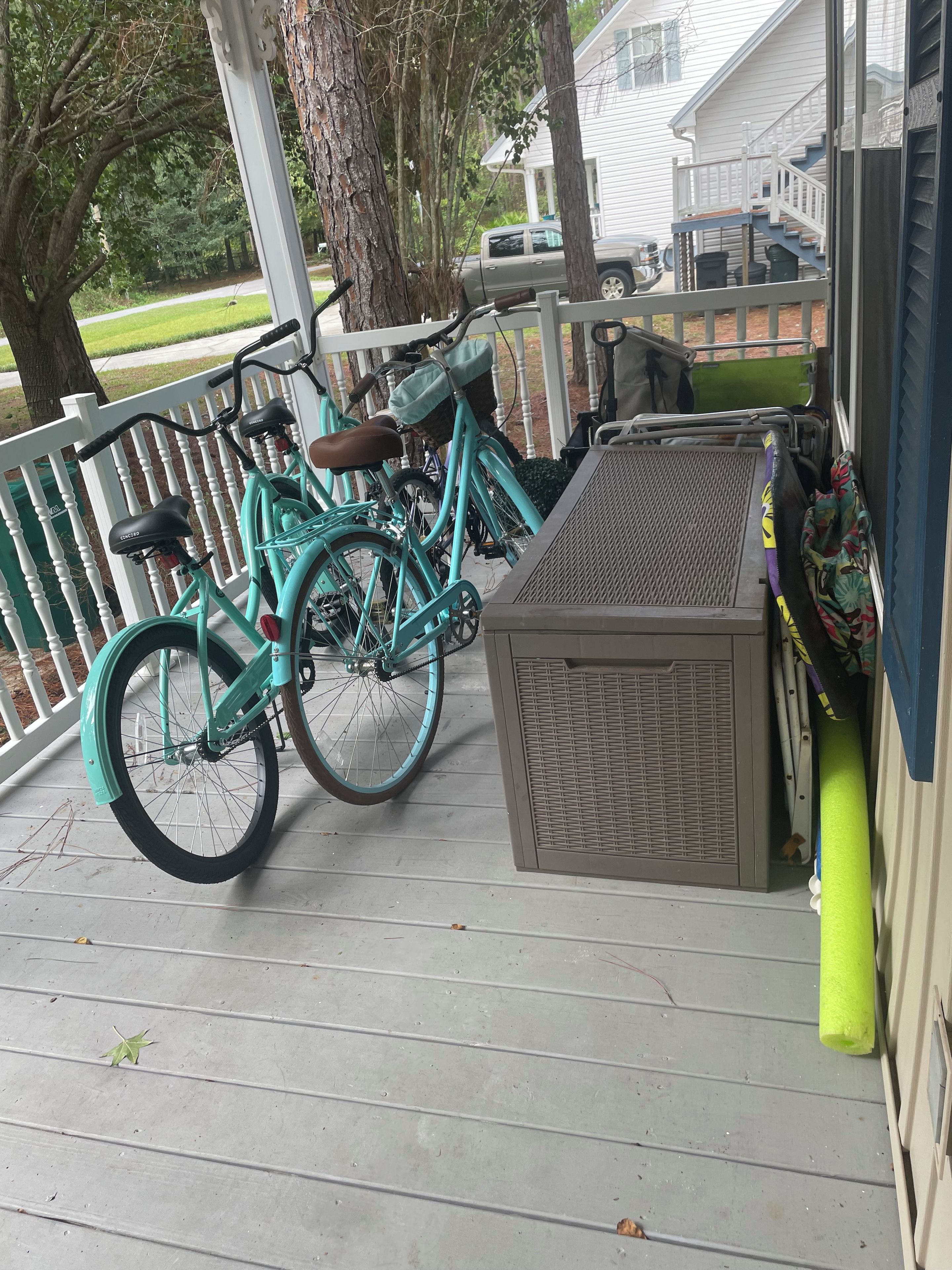 Un porche con dos bicicletas, una parrilla y una zona cubierta con un banco.