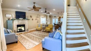 Un salón espacioso con chimenea, un sofá azul y una escalera que sube a un nivel superior.