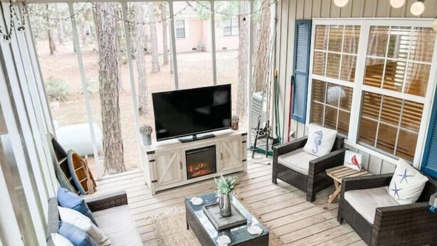 Un patio acogedor con mobiliario de mimbre, un televisor de pantalla plana y una chimenea.