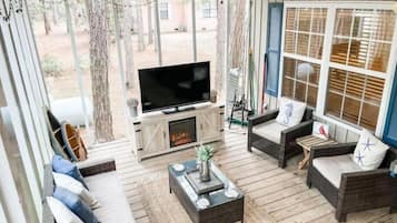 Un espace patio accueillant, doté de meubles en osier, d’un téléviseur à écran plat et d’une cheminée.