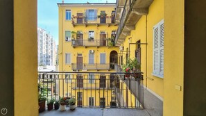 A yellow building with multiple balconies, potted plants, and a visible staircase. - Italianway Comfort - Bligny 19 D (Milan)