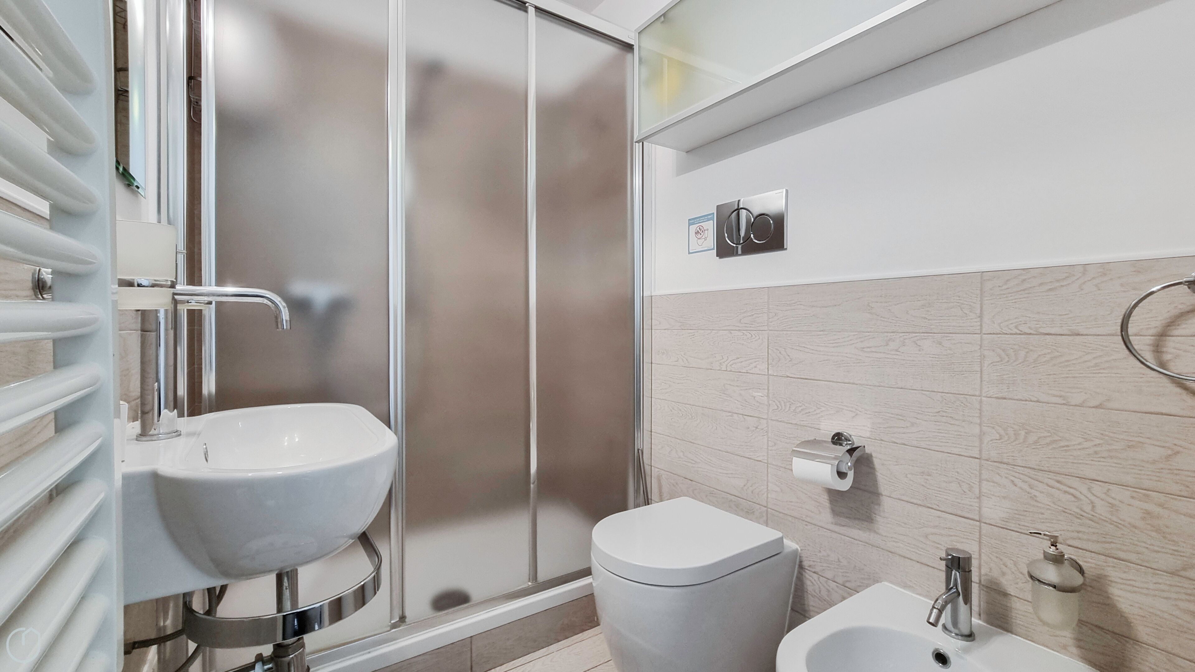 A modern bathroom with a glass shower enclosure, a sink, a bidet, and a toilet.