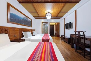 Ein Hotelzimmer mit zwei Betten, einem Fernseher, Holzmöbeln und einer gemusterten Decke.