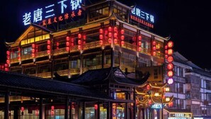 A traditional Chinese building with multiple stories, illuminated by red lanterns and featuring signage in Chinese characters. - Zhangjiajie Wulingju Inn (Wulingyuan Scenic Area) (Zhangjiajie)