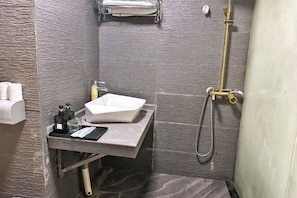 Ein Badezimmer mit einem weißen Waschbecken, einem Handtuchhalter und einer Dusche.
