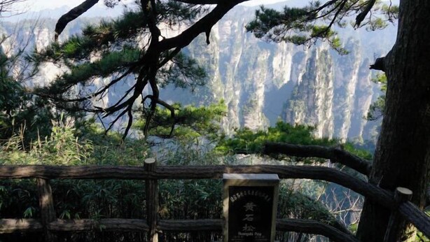 A wooden fence with a plaque in front of a mountainous landscape. - Zhangjiajie Wulingju Inn (Wulingyuan Scenic Area) (Zhangjiajie)