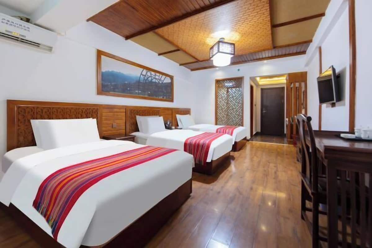 Une chambre d’hôtel avec deux lits, un plafond en bois, une télévision et un bureau.