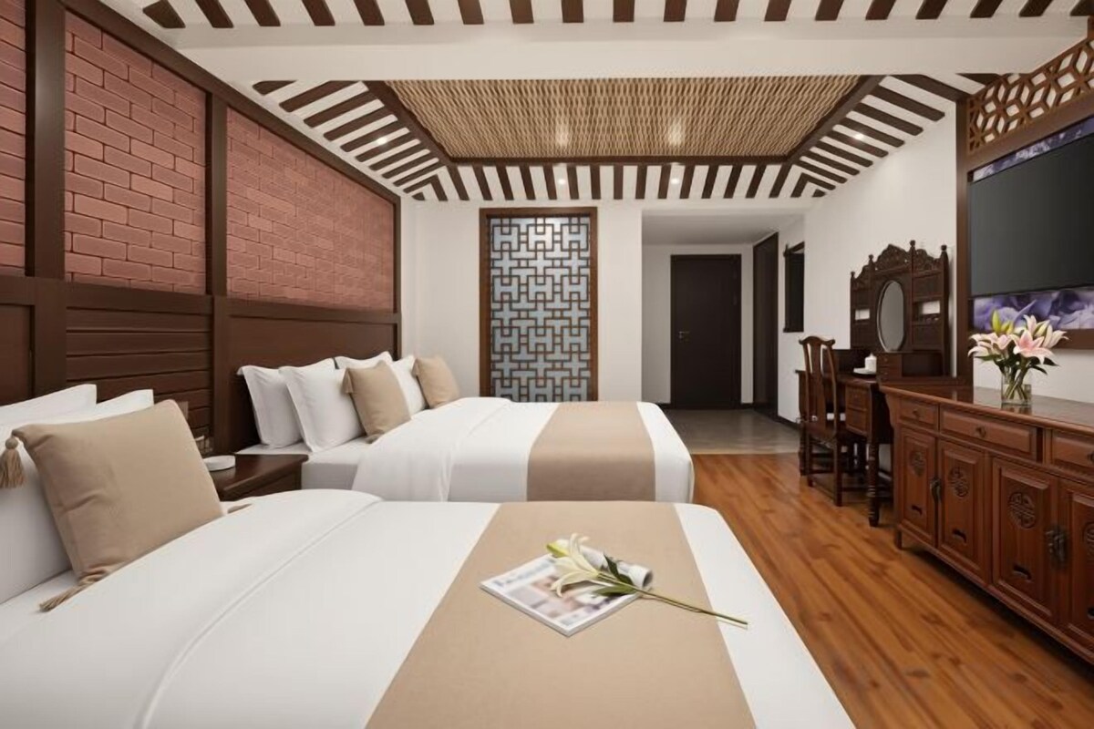 A hotel room with two beds, a wooden cabinet, a mirror, and a television.