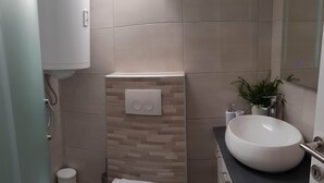 A compact bathroom with a toilet, sink, and a wall-mounted light fixture. - Apartment Prijeboj 2 - Plitvice Lakes 6km from apartment (Prijeboj)