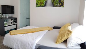 A modern hotel room with a bed, a TV, a desk, and a door. - Apartment Prijeboj 2 - Plitvice Lakes 6km from apartment (Prijeboj)