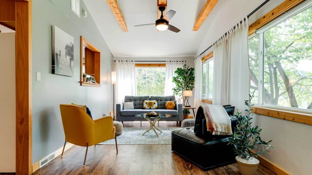 A modern living room with a sofa, armchairs, a coffee table, and a ceiling fan.