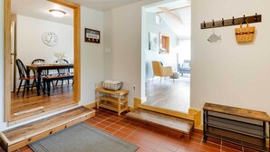 A modern interior with a wooden dining table, chairs, and a bench. There is a wall clock and a sign that reads "Live House."