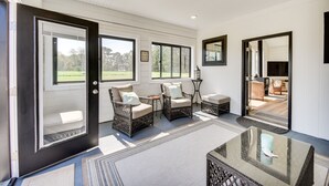 A spacious room with large windows, wicker furniture, and a glass table. - Stunning Chesapeake Bay Farmhouse w/ Dock & Kayaks (Machipongo)