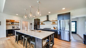 A modern kitchen with a large island, stainless steel appliances, and pendant lighting. - Stunning Chesapeake Bay Farmhouse w/ Dock & Kayaks (Machipongo)