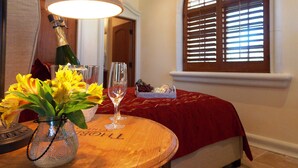Ein Zimmer mit einem Holztisch, einer Blumenvase mit gelben Blumen, einer Champagnerflasche und einem Glas.