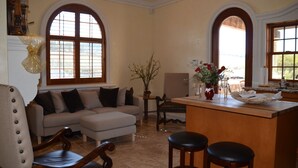 Ein geräumiges Wohnzimmer mit einer großen Couch, einem Holzespeisetisch und einer Küchenzeile mit Bar.