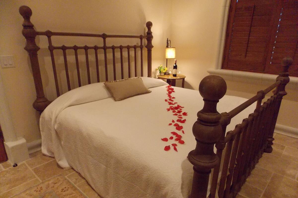 A neatly made bed with a wooden headboard, a bedside table with a lamp, and a decorative item on the nightstand.