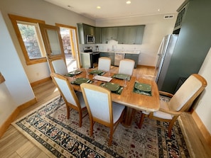 A dining area with a wooden table, chairs, and a patterned rug. - Stunnding Views in Every Room! 3 Full Bathrooms! (Kalispell)